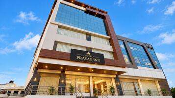 Un hotel de varios pisos con un letrero destacado que dice 'Hotel Prayag Inn'.