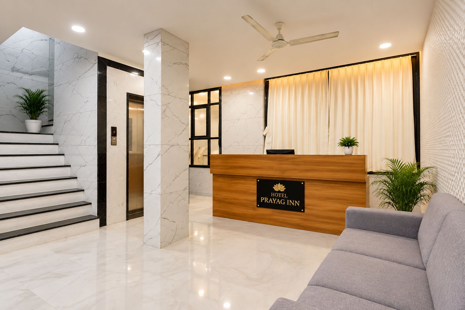 Zona de recepción de un hotel con una escalera de mármol, un mostrador de recepción y un ventilador de techo.