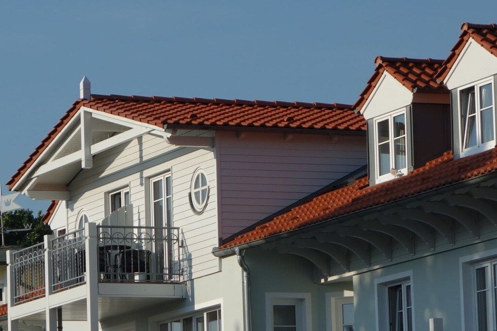 Ein zweistöckiges Gebäude mit einem Balkon und einem roten Ziegeldach.