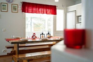 A dining area with a wooden table set for four, a red curtain, and a window with blinds.