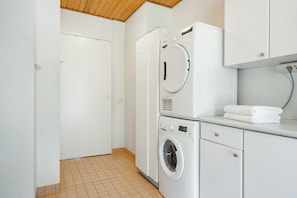 A laundry room with a washing machine, dryer, and stacked towels.