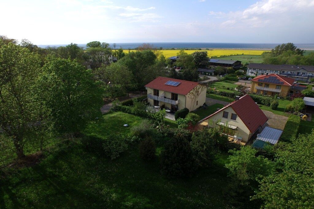 Un quartier résidentiel avec des maisons, de vastes pelouses verdoyantes et une vue lointaine sur la mer.