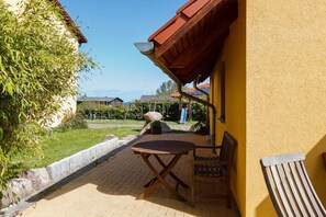 A patio with a table and chairs, a yellow wall, and a view of the landscape. - Holiday home in Kägsdorf with swimming pool (Kägsdorf)