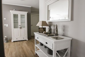 Una habitación con un armario blanco, un espejo y una lámpara sobre una consola blanca.