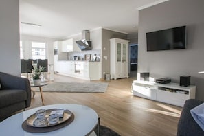 A modern living room with a flat-screen TV, a coffee table, and a sofa. - Villa Louisa 40 - Lighthouse (Ostseebad Sellin)