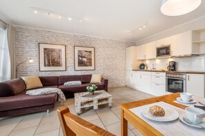 Ein modernes Wohnzimmer mit einer Couch, einem Couchtisch und einem Esstisch mit einem Brot.