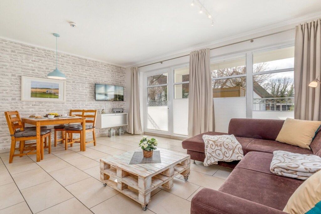 A living room with a sofa, a coffee table, and a dining area with chairs and a table.