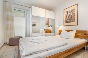 Ein Hotelzimmer mit Bett, Schrank, Nachttisch, Lampe und einem gerahmten Bild an der Wand.