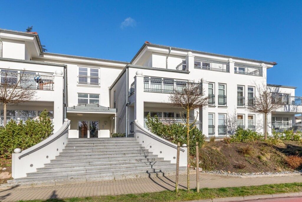 Un edificio residencial de varios pisos con una escalera central que conduce a la entrada.
