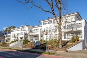 A multi-story residential building with balconies, a staircase leading to the entrance, and a clear sky. - Dune Residence Queen Augusta 5 (Ostseebad Binz)