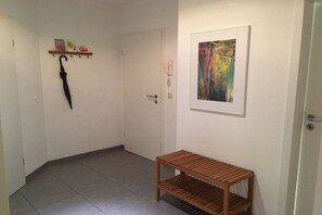 A hallway with a wooden bench, a door, and a wall-mounted telephone. - Dune Residence Queen Augusta 3 (Ostseebad Binz)