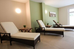 Una habitación con tres sillones, una mesita con una planta y un cuadro colgado en la pared.