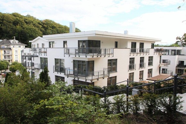 Un edificio residencial de varios pisos con balcones, ventanas amplias y techo plano.