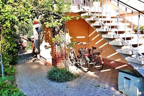 A bicycle parked next to a staircase with a metal railing, a brick wall, and a small garden area. - Apartment "Im Wiesengrund" (Kühlungsborn)