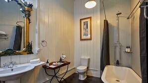 A bathroom with a freestanding bathtub, a pedestal sink, a toilet, and a mirror with an ornate frame. - The Factory (Hapuku)
