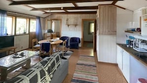 Ampla sala de estar com sofá, mesa de jantar e cozinha equipada com armários e eletrodomésticos.