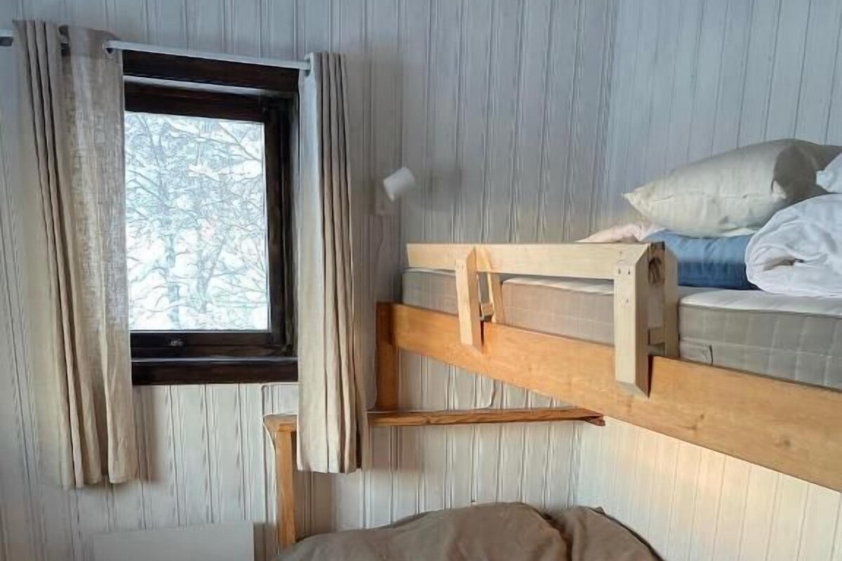 A bunk bed room with a window, a radiator, and a striped rug.