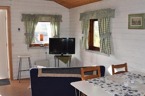 A room with a television, a table with a floral tablecloth, and a couch.
