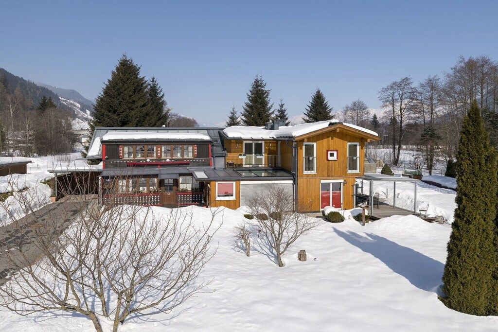 A two-story house with a garage, a covered porch, and a snow-covered landscape.