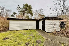 Ein eingeschossiges Gebäude mit Garage und einer kleinen Gartenhütte.