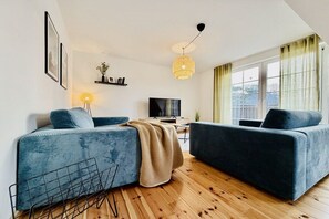 A modern living room with two sofas, a TV, and a wooden floor. - Holiday apartment with 2 bedrooms (Dierhagen)