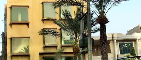 A hotel with a signboard, multiple windows, and parked cars.