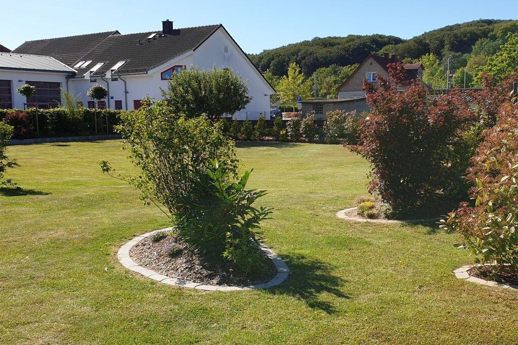 A residential area with houses, a well-maintained lawn, and a small tree in the center.