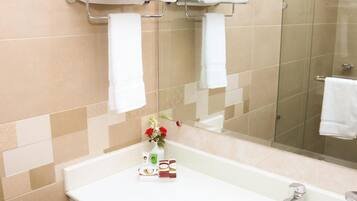 A bathroom with a white sink, a glass shower enclosure, and a towel rack with folded towels.