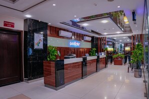 A hotel reception desk with a digital sign, a map, and a flag.