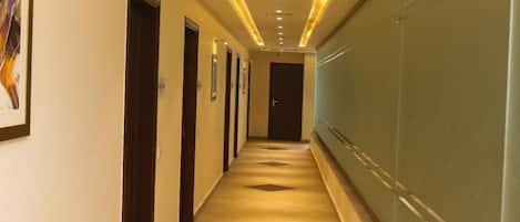 Un pasillo de hotel con una larga extensión, puertas y una pared de vidrio en un lateral.