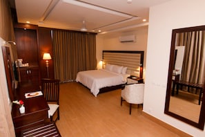 A hotel room with a bed, bedside table, lamp, and a mirror.