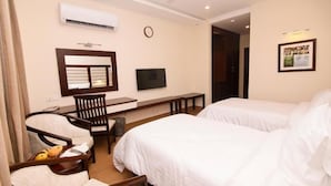 Quarto de hotel com duas camas, uma escrivaninha, uma cadeira e uma televisão.