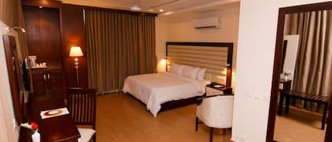 A hotel room with a bed, bedside table, lamp, and a mirror.