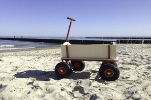 Eine Strandansicht mit einem Bollerwagen.