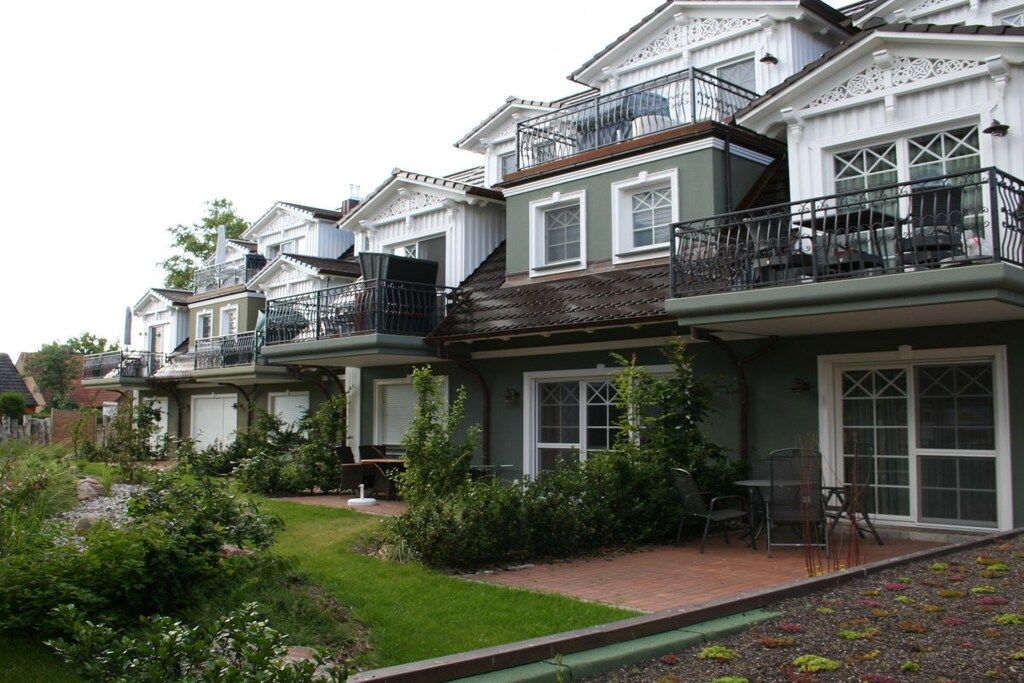 A row of townhouses with balconies, a garden area, and a patio with outdoor furniture.