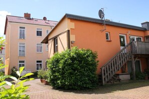 A two-story building with a brick pathway leading to a wooden staircase. - "TUSCANY" with balcony and 2 bedrooms (Waren)
