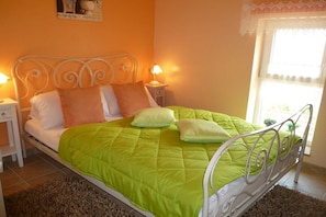 A bed with a green quilt, white headboard, and two bedside lamps. - "TUSCANY" with balcony and 2 bedrooms (Waren)