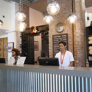 A reception desk with a sign indicating the number 4, a clock, and a wall with a list of locations.