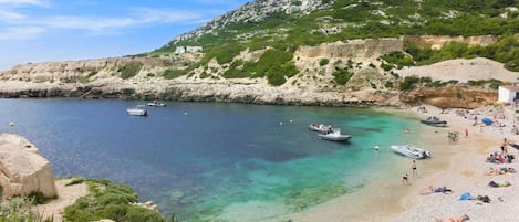 Une plage côtière avec des bateaux, des gens et un paysage rocheux.