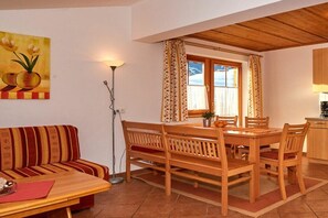 A dining area with a wooden table and chairs, a sofa, and a painting on the wall. - Holiday apartment in Filzmois with barbecue (Filzmoos)