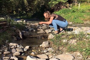 A person crouching near a rocky stream in a natural setting. - Holiday apartment in Filzmois with barbecue (Filzmoos)