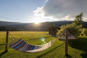 A hammock in a grassy field with a wooden cabin in the background. - Holiday apartment in Filzmois with barbecue (Filzmoos)