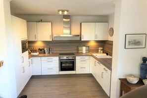 Eine moderne Küche mit weißen Schränken, einem eingebauten Ofen und einer Holz Arbeitsplatte.