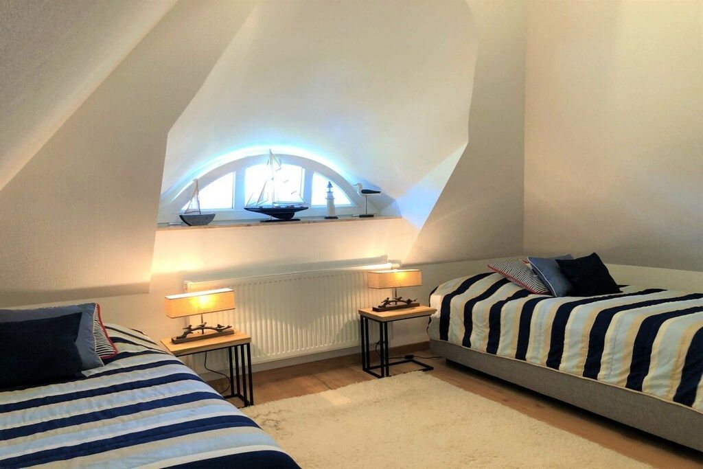Quarto com duas camas, uma janela decorada com um navio e um radiador.