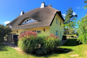 A house with a thatched roof, a yellow facade, and a well-maintained garden. - Beach villa "Meerlust" (Ostseebad Dierhagen Strand)
