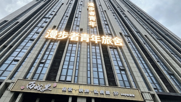 Un edificio alto con señalización iluminada que indica un albergue juvenil.
