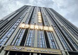 A tall building with illuminated signage indicating a youth hostel. - Slow Walker Youth Hostel (Chengdu)
