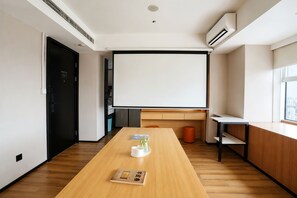A modern meeting room with a large projection screen, wooden flooring, and a minimalist design. - Slow Walker Youth Hostel (Chengdu)