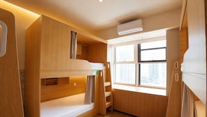 Una habitación compacta con literas, una ventana con vista a la ciudad y aire acondicionado integrado.