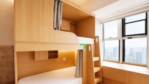 Una cama litera con vistas a la ventana, paredes de madera y un pequeño estante.